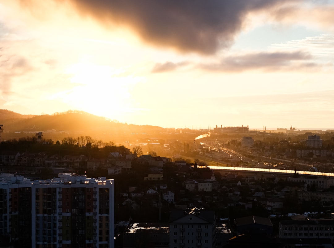 A construction crane stands tall over a city skyline at sunrise, illustrating new development and growth in urban housing.