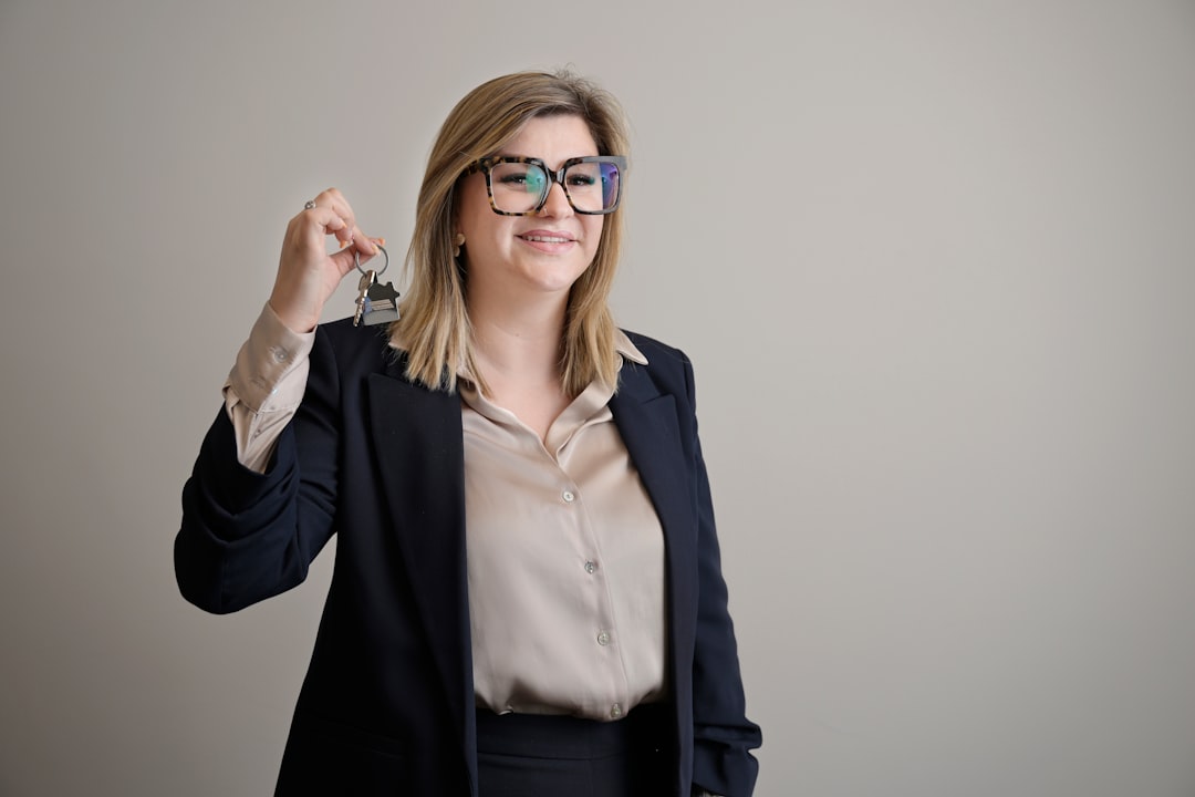 A professional and modern real estate closing with two people shaking hands over a set of house keys on a clean desk, signifying a successful sale.
